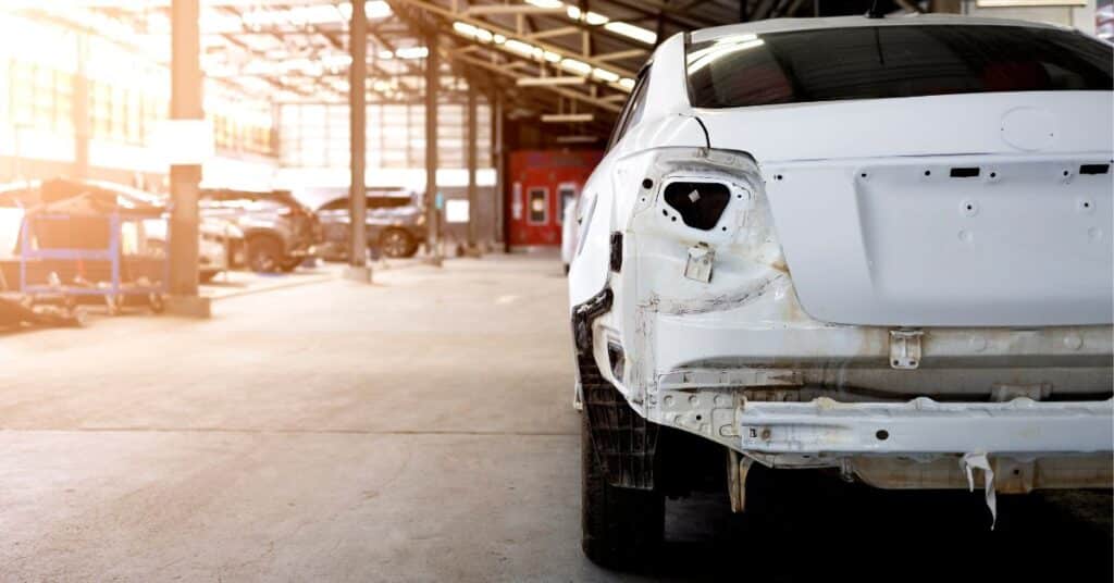 White car with rear panels removed during certified aluminum body repair at West Delray Collision