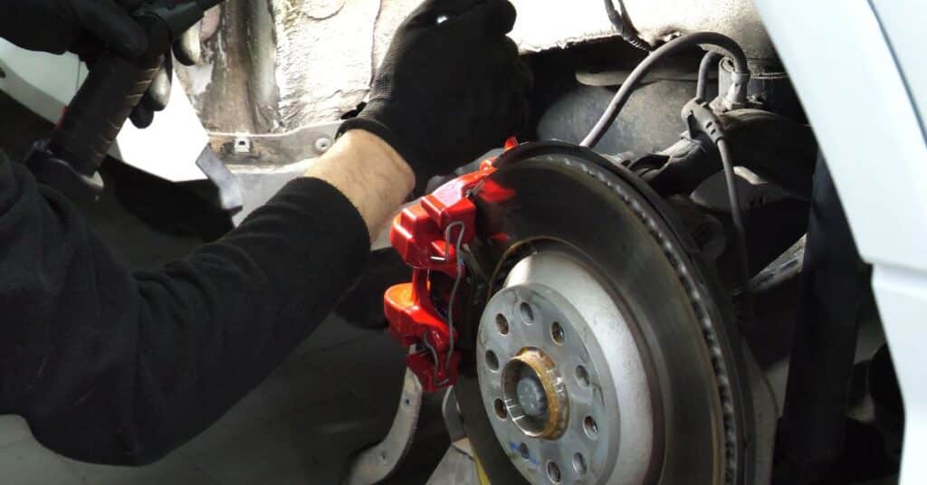 Technician inspecting brake and suspension components after collision damage