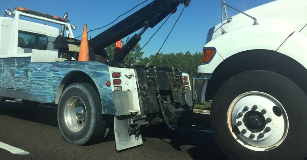 White SUV on a flatbed tow truck during daytime emergency roadside assistance.