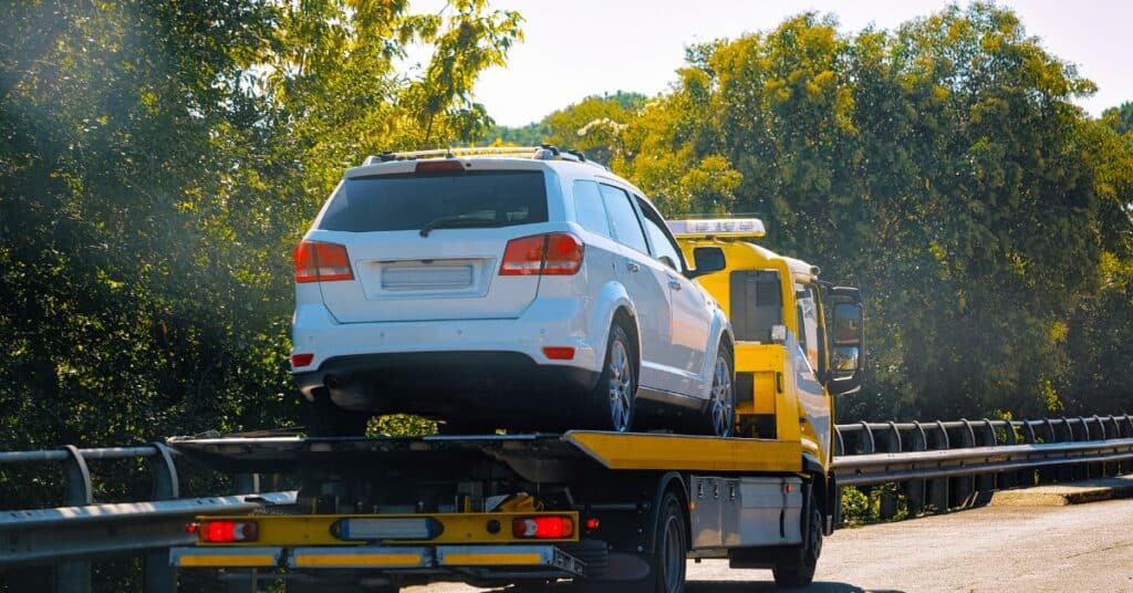 Heavy-duty tow truck towing a large commercial vehicle on the highway.
