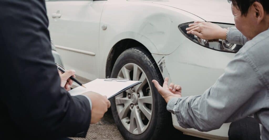 Auto body technician inspecting vehicle damage after a car accident